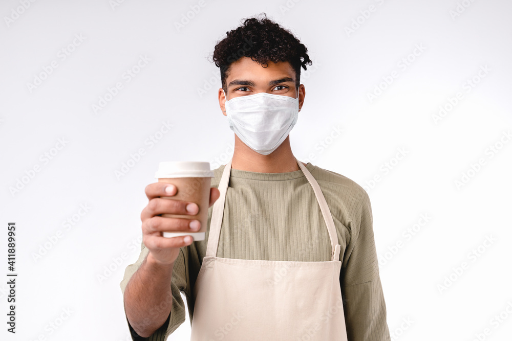 Young mixed-race barista in medical mask against Covid 10 giving a cup of coffee isolated over white background Young mixed-race barista in medical mask against Covid 10 giving a cup of coffee isolated over white background