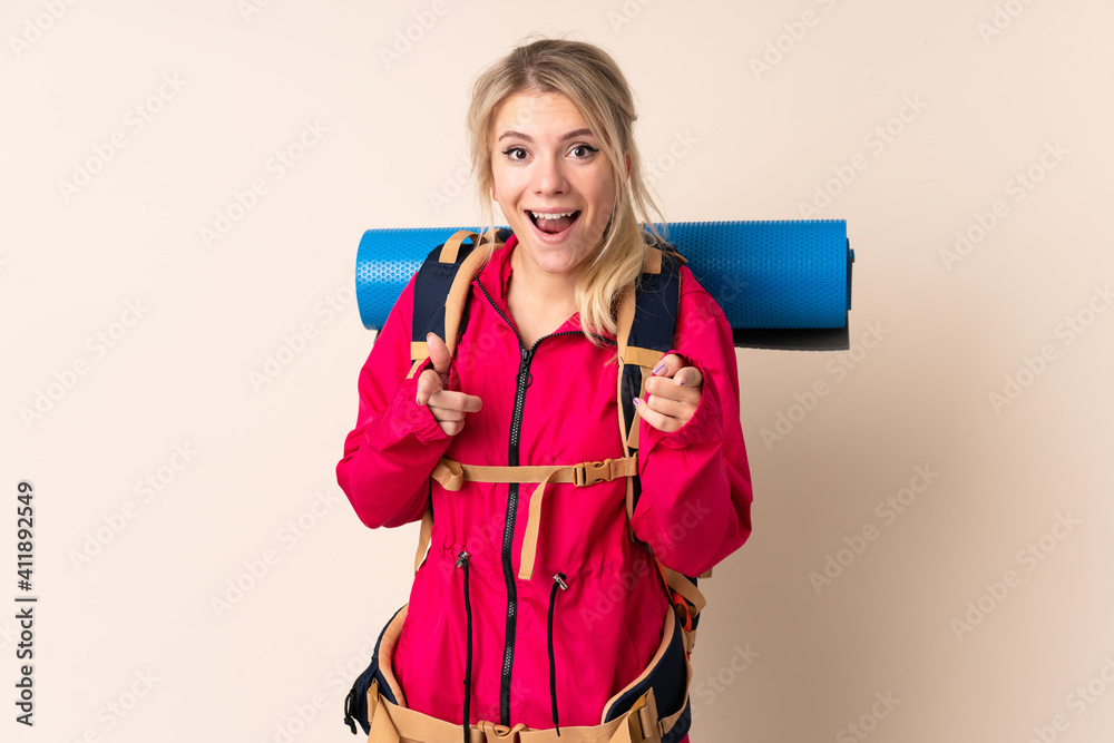 Mountaineer woman with a big backpack over isolated background points finger at you Mountaineer woman with a big backpack over isolated background points finger at you