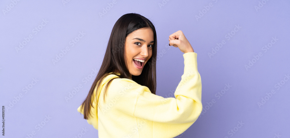 Young caucasian woman over isolated background doing strong gesture - obrazy, fototapety, plakaty 
