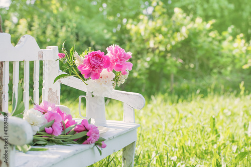 Fototapeta Naklejka Na Ścianę i Meble -  peony in jug on white wooden bench in summer garden