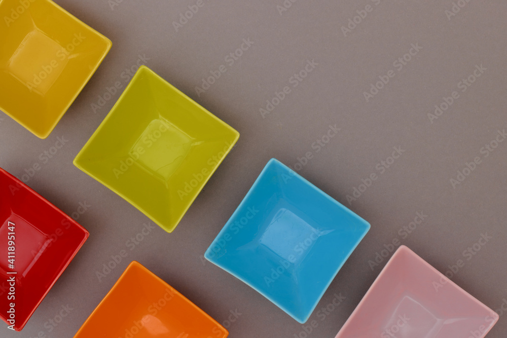 Colorful empty rectangular bowls on gray background with copy space. Flat lay view. Colorful empty rectangular bowls on gray background with copy space. Flat lay view.