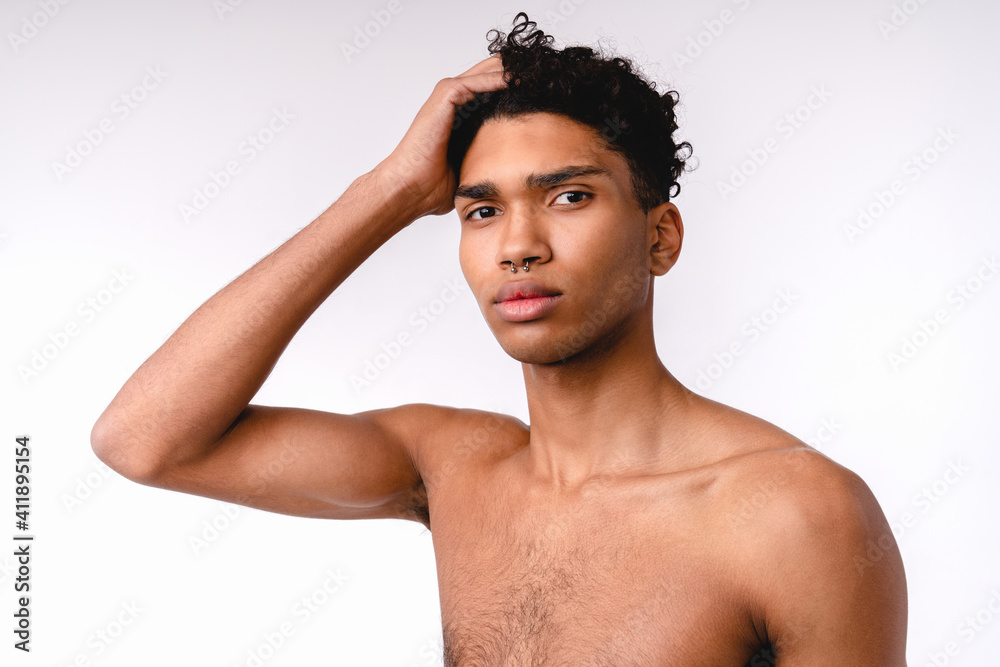 Fototapeta premium Attractive 20s african man touching his hair shirtless isolated over white background