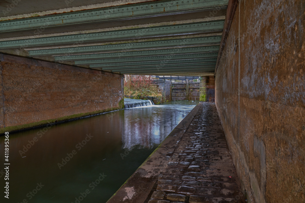 Under main road bridge narrow footpath along Rochdale canal