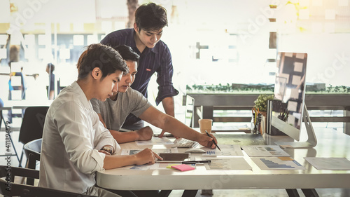 Fotografia Young Asian businessman are meeting at working and pointing to analyzing charts and graphs