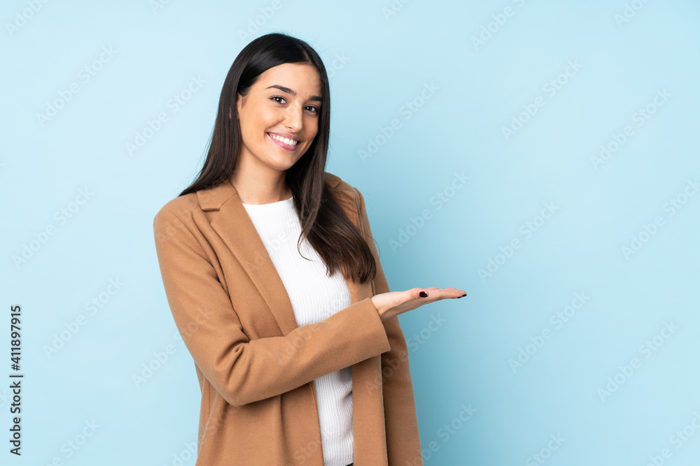 Young caucasian woman isolated on blue background presenting an idea while looking smiling towards Young caucasian woman isolated on blue background presenting an idea while looking smiling towards