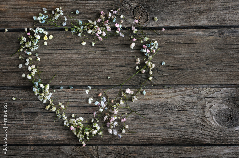 Heart symbol made of small flowers of gypsophila on a wooden background. View from above. Selective focus. Сopy space for your text Heart symbol made of small flowers of gypsophila on a wooden background. View from above. Selective focus. Сopy space for your text