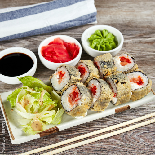 japanese sushi rolls in a rectangular plate on a light wooden table