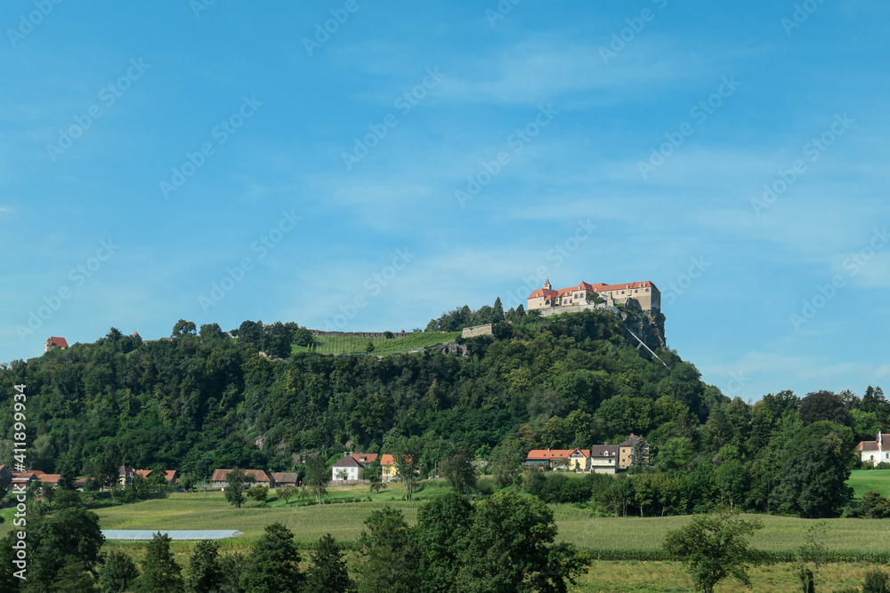 A distant view on the Riegersburg castle in Austria towering above the area. Clear blue sky above the castle. The massive fortress was build on the rock. Defensive structure from the middle ages. Calm