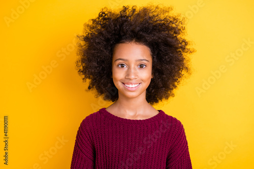 Photo of satisfied dark skin little girl toothy smile look camera wear sweater isolated on yellow color background