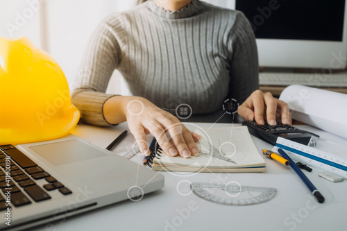 Two colleagues discussing data working and tablet, laptop with on on architectural project at construction site at desk in office