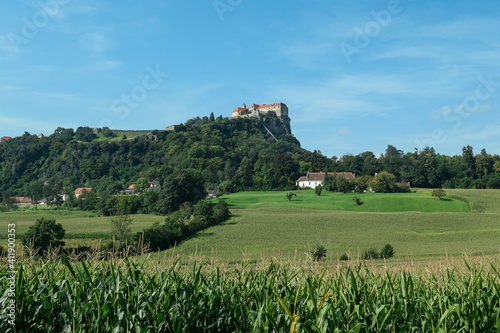 Riegersburg castle in Austria towering above the area. There are mais crops ripening on the field in front. Clear blue sky above the castle. The massive fortress was build on the rock. Middle ages photo