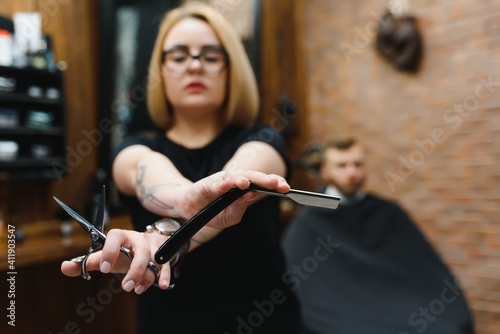 Portrait of fashion woman barber hairstylist with scissors in hand in the barbershop