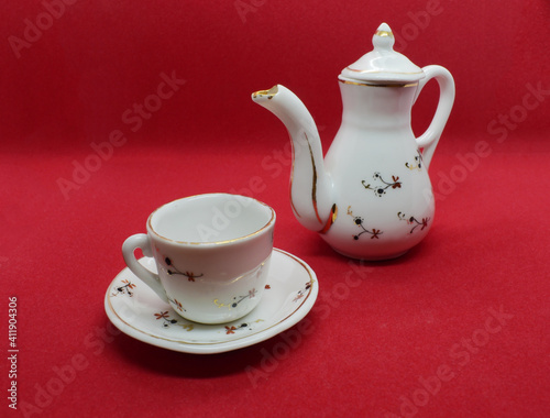 Teapot and cup with saucer on a red background