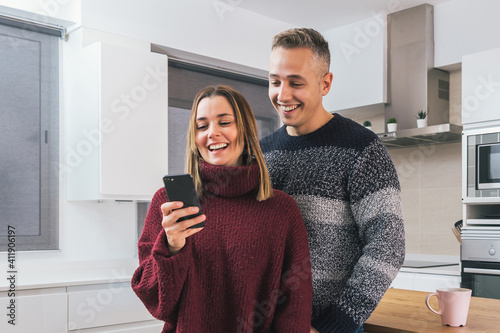 Young couple  man and woman having a great time together looking a mobile phone in the apartment. Couple life at home concept