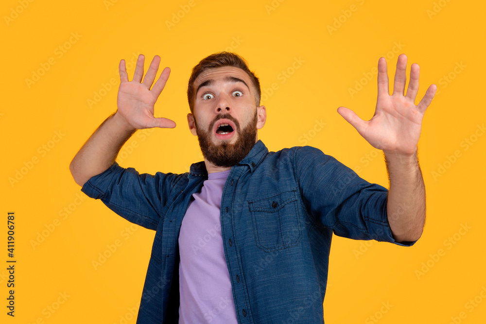 Scared Caucasian man making frightened gesture with his hands, trying to defend himself on orange studio background Scared Caucasian man making frightened gesture with his hands, trying to defend himself on orange studio background