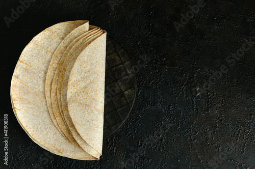 Fresh homemade tortillas on a black background. Top view. Free space for your text
