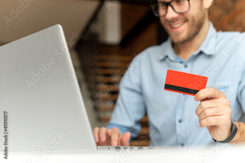 A credit card in male hands. Close-up cropped picture a guy is using a laptop to pay online, transferring money, receiving payment on his bank account. E-banking concept