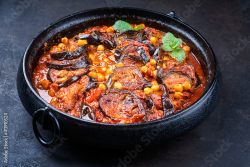 Modern style slow cooked Lebanese vegetarian eggplant stew maghmour served with chickpeas as close-up in a design pot photo