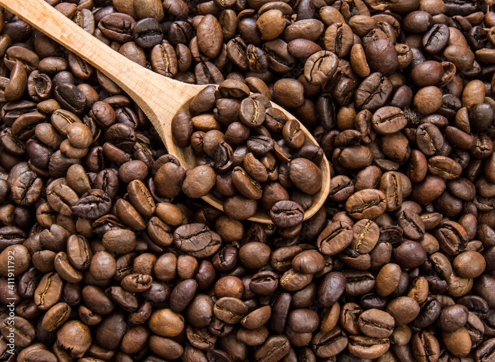 A spoonful of beans lies on top of the spilled coffee. A spoonful of beans lies on top of the spilled coffee.