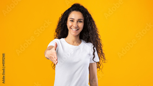 Lady Offering Hand For Handshake Greeting Posing Over Yellow Background