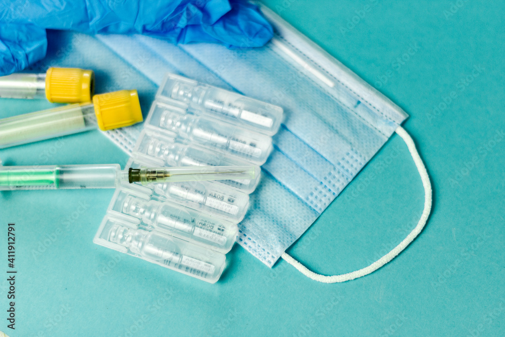 Medical vials for injection, syringe for injection, mask gloves on a blue background. Admission vaccination, flu shot. Medical vials for injection, syringe for injection, mask gloves on a blue background. Admission vaccination, flu shot.