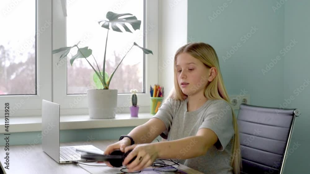 Teenage girl in headphones having online lesson at home Teenage girl in headphones having online lesson at home