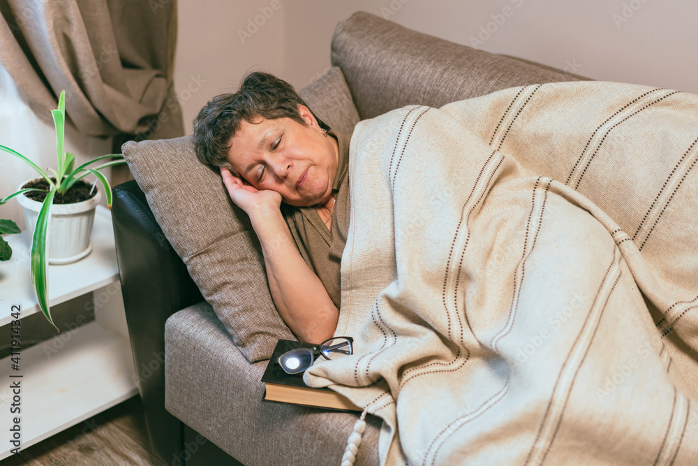 Senior woman felt asleep while reading on sofa Senior woman felt asleep while reading on sofa