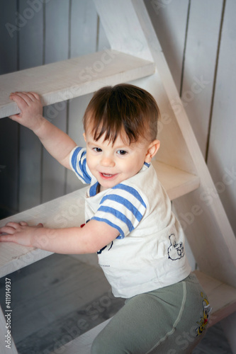 A young brown-haired boy climbing white stairs smiling
