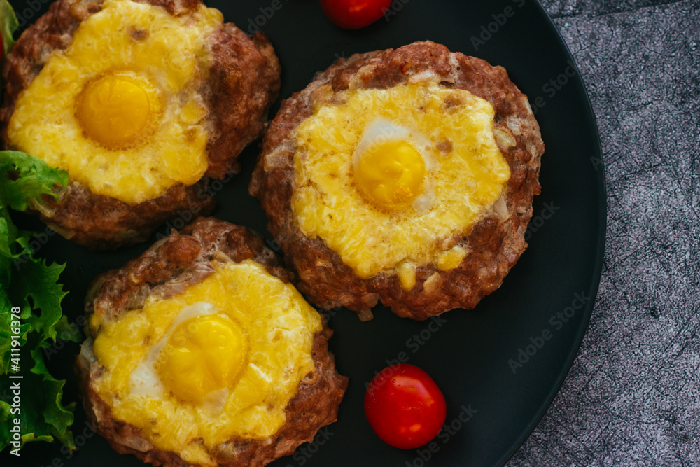 Beefsteak with egg on a plate. Delicious hot dish. The dish is decorated with cherry tomatoes and herbs. Beefsteak on a plate Beefsteak with egg on a plate. Delicious hot dish. The dish is decorated with cherry tomatoes and herbs. Beefsteak on a plate