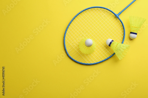 Badminton racket and shuttlecocks on yellow background, flat lay. Space for text © New Africa