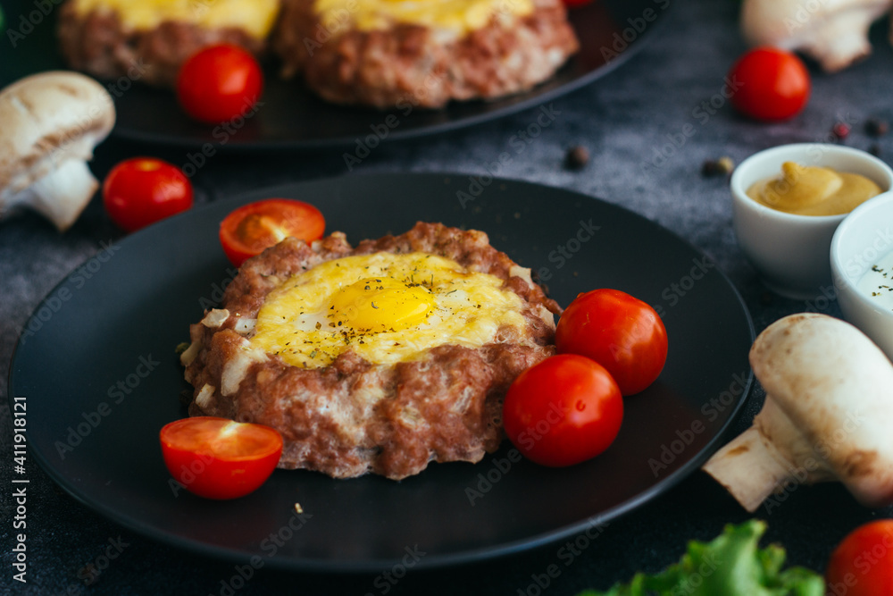 Beefsteak with egg on a plate. Delicious hot dish. The dish is decorated with cherry tomatoes and herbs. Beefsteak on a plate Beefsteak with egg on a plate. Delicious hot dish. The dish is decorated with cherry tomatoes and herbs. Beefsteak on a plate