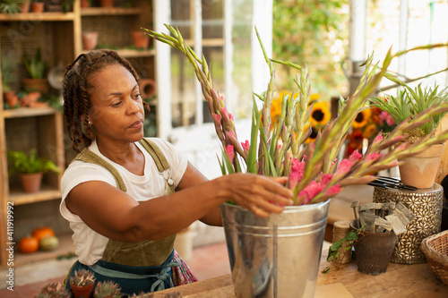 Female florist arranging flowers in bucket in shop owner