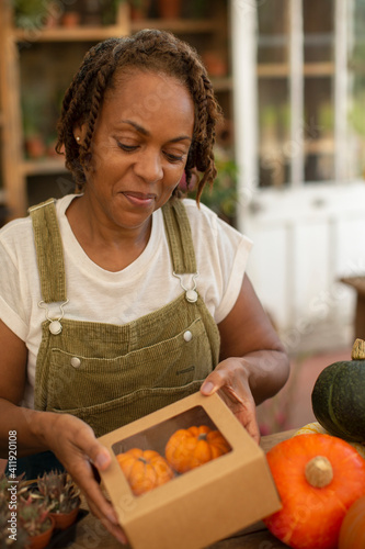 Female florist boxing small pumpkins in shop