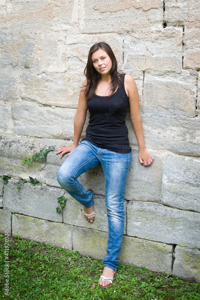 Summer portrait of a shapely young woman who is wearing casual clothes in front of a beautiful old wall Summer portrait of a shapely young woman who is wearing casual clothes in front of a beautiful old wall