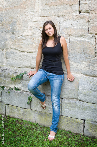 Summer portrait of a shapely young woman who is wearing casual clothes in front of a beautiful old wall
