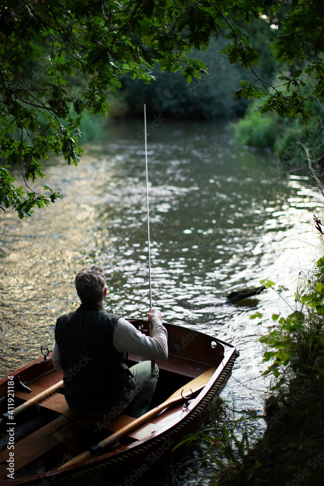 Man fly fishing from boat on river Man fly fishing from boat on river