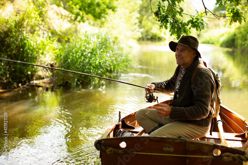 Man fly fishing from rowboat on sunny river photo