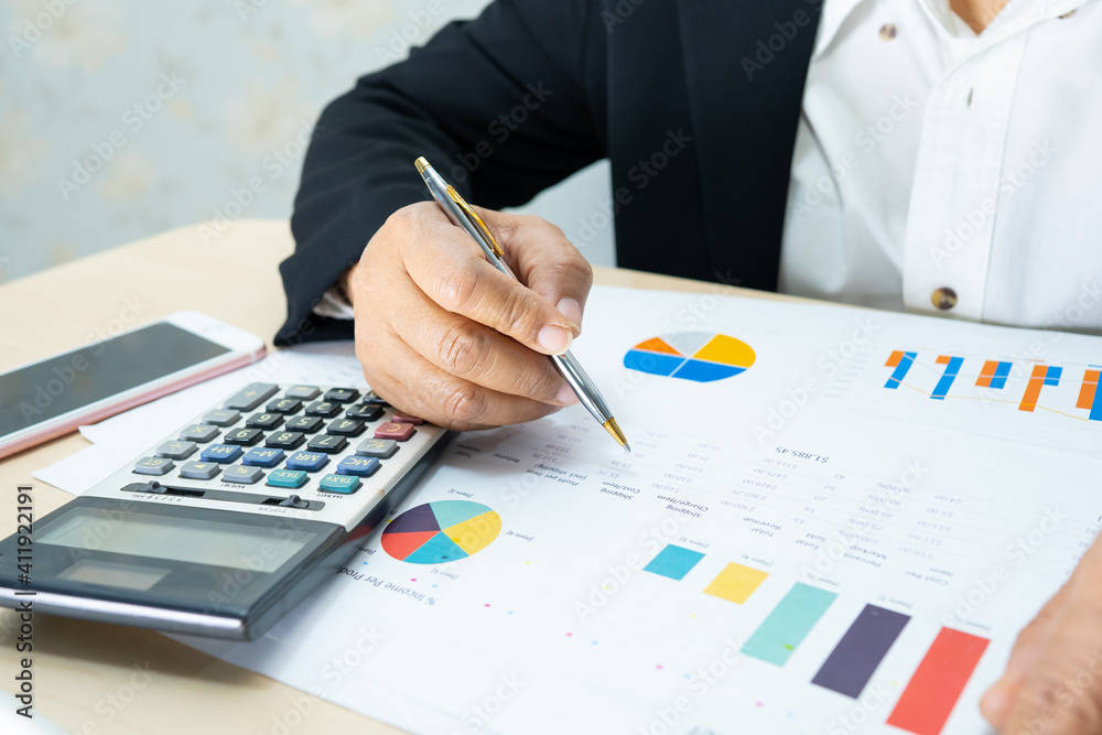 Asian accountant working and analyzing financial reports project accounting with chart graph and calculator in modern office, finance and business concept. Asian accountant working and analyzing financial reports project accounting with chart graph and calculator in modern office, finance and business concept.