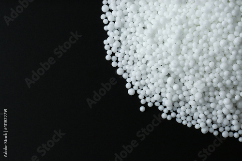 Pellets of ammonium nitrate on black background, flat lay with space for text. Mineral fertilizer