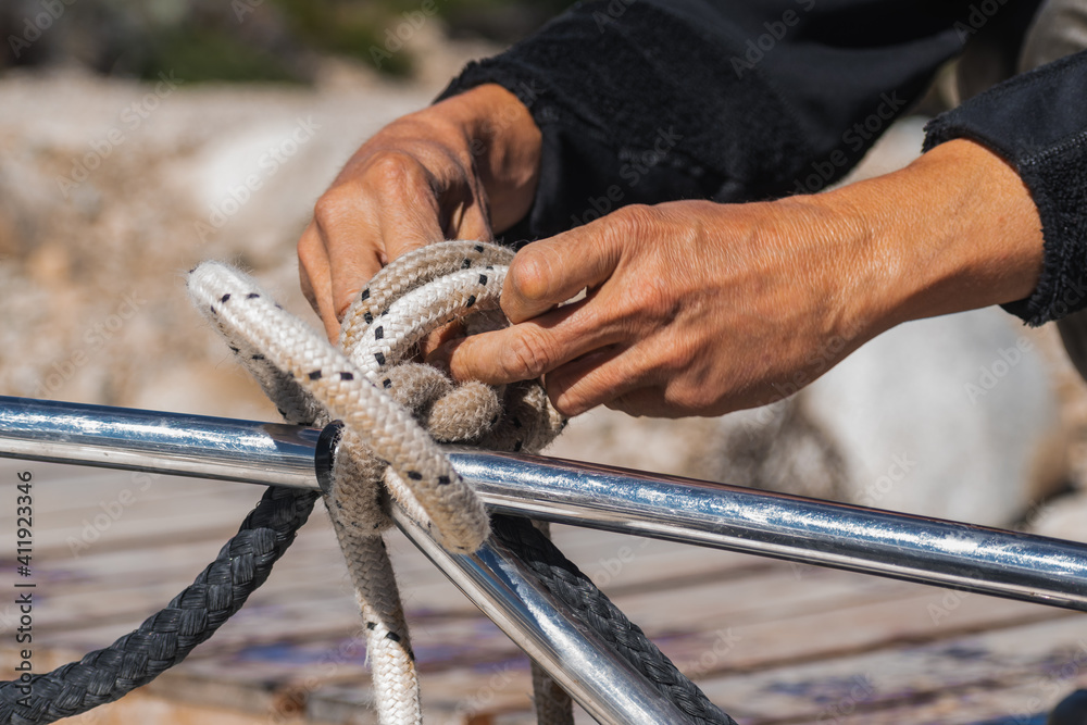 adult man's hands tying a rope to the boat