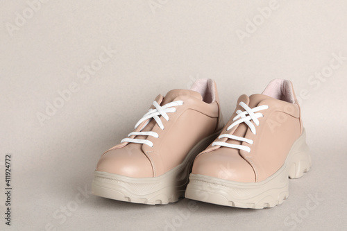 Pair of stylish shoes with white laces on beige background