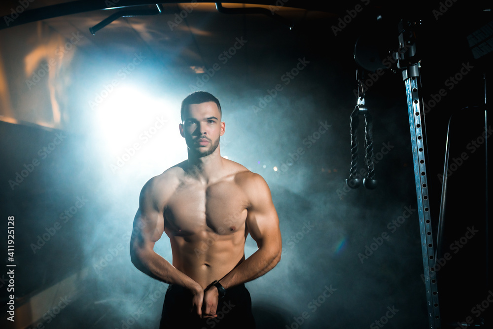 Portrait of an athletic man standing shirtless and looking away with hands on his hips