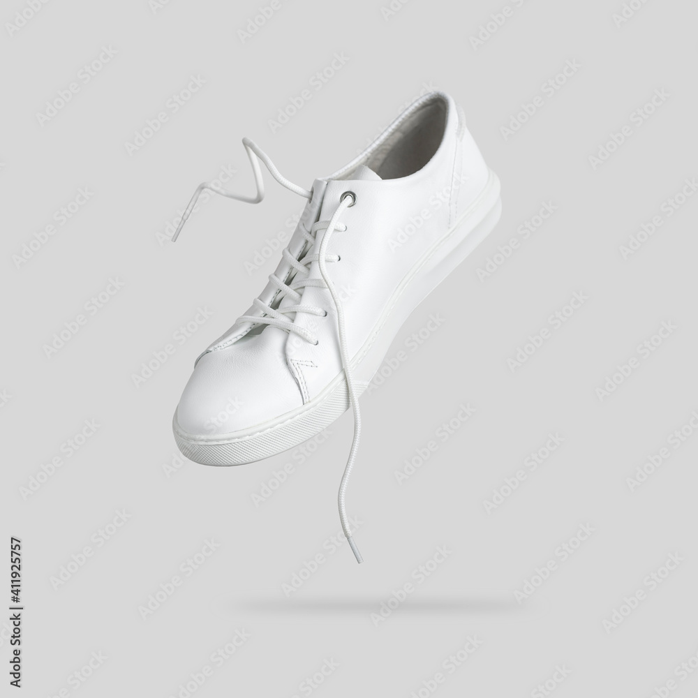 Flying white leather womens sneakers isolated on gray background. Fashionable sports casual shoes. Creative minimalistic layout with footwear Mock up for your design Advertising for shoe Stock-foto | Adobe Stock