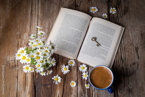 Obraz na płótnie A cup of coffee with a book and daisies w salonie