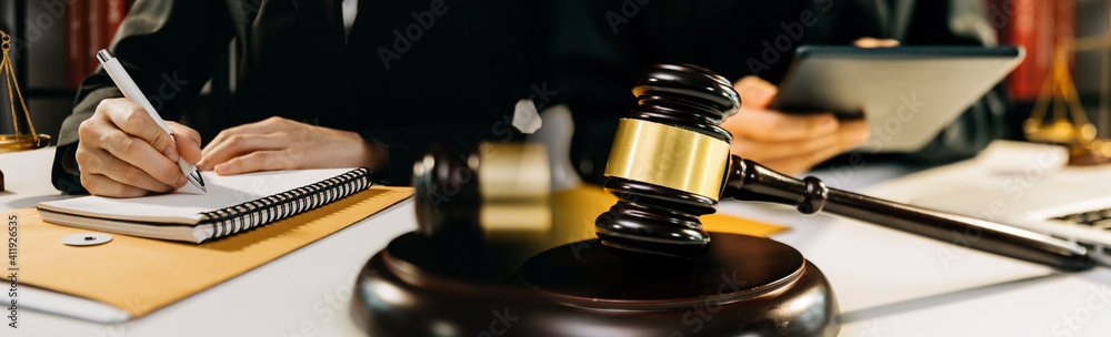 Business and lawyers discussing contract papers with brass scale on desk in office. Law, legal services, advice, justice and law concept picture with film grain effect Business and lawyers discussing contract papers with brass scale on desk in office. Law, legal services, advice, justice and law concept picture with film grain effect