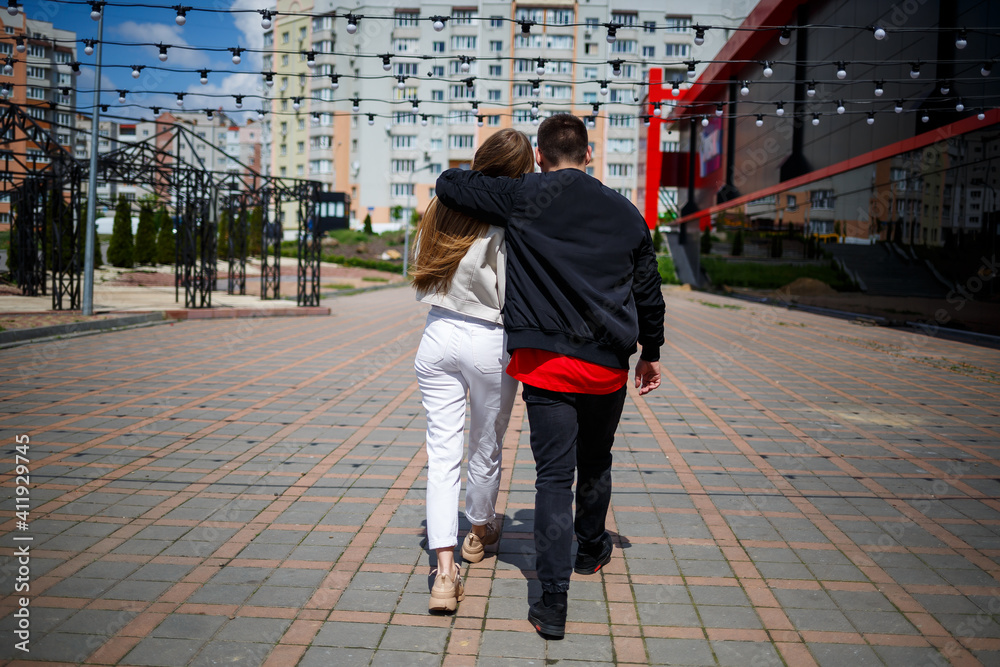 Stylish young girl with blond hair of European appearance and a guy in a black jacket. Urban walk of a couple in love, modern fashion in casual style. Happy relationship concept Stylish young girl with blond hair of European appearance and a guy in a black jacket. Urban walk of a couple in love, modern fashion in casual style. Happy relationship concept