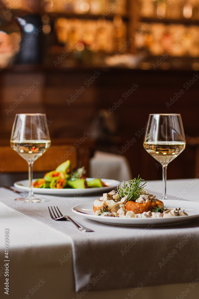 Stuffed mushrooms filled with cheese, mushroom stem and microgreen on the white plate with a glass of wine