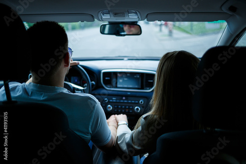 Loving couple in a car hug and hold hands while traveling. Stylish young girl with blond hair of European appearance and a guy in a white polo. Happy relationship concept © Дмитрий Ткачук