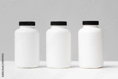 Blank white jars for food supplement on the table front view background.