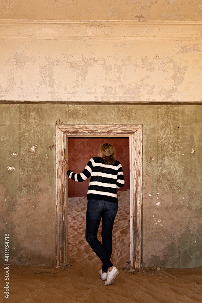 Mujer joven mirando una habitación en la ciudad fantasma de Kolmanskop, Namibia.